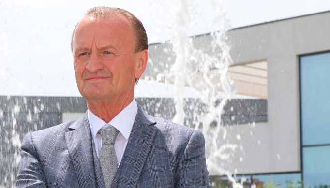 Mann im Anzug vor modernem Gebäude mit Brunnen.