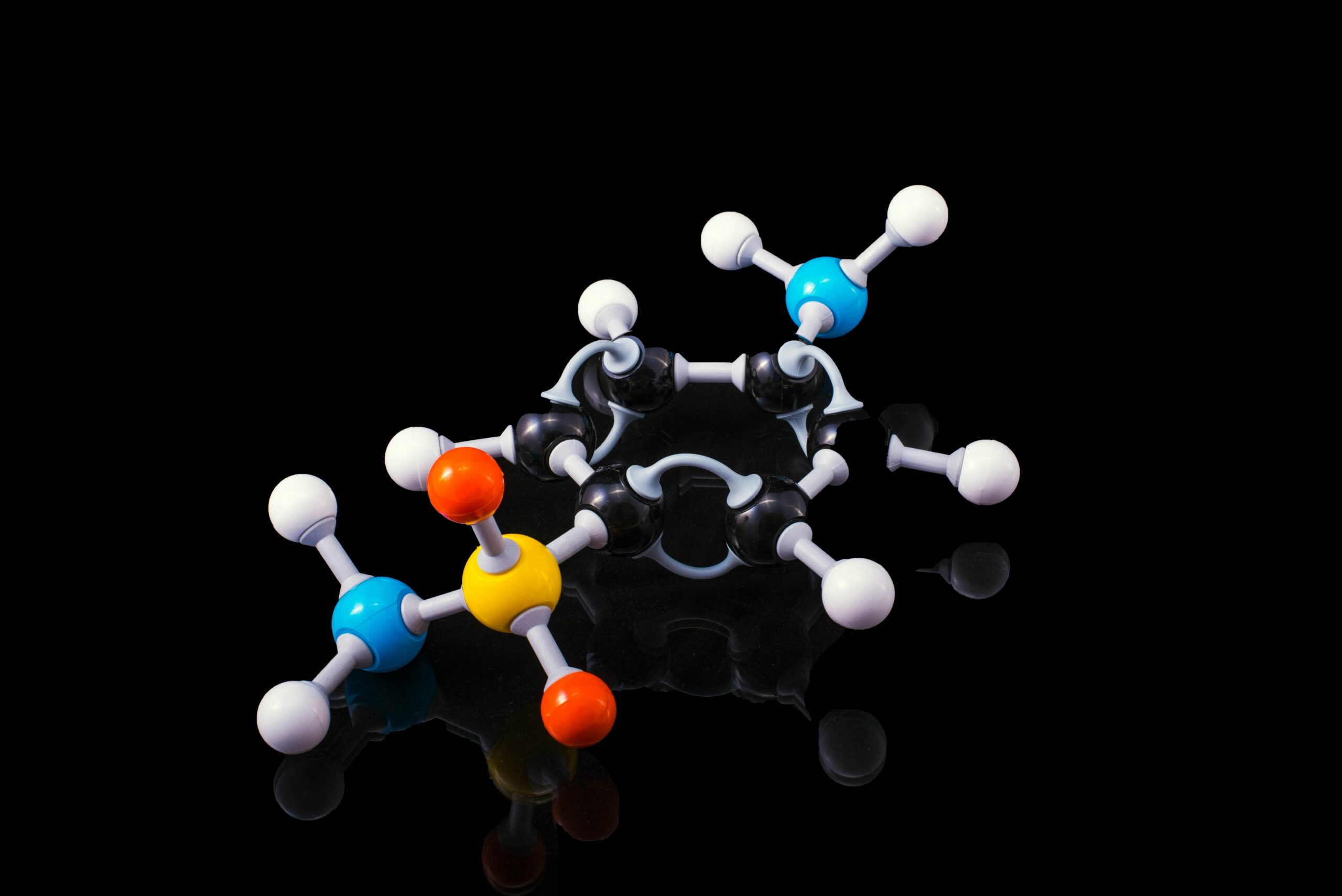 Molekülmodell mit farbigen Atomen auf schwarzem Hintergrund.