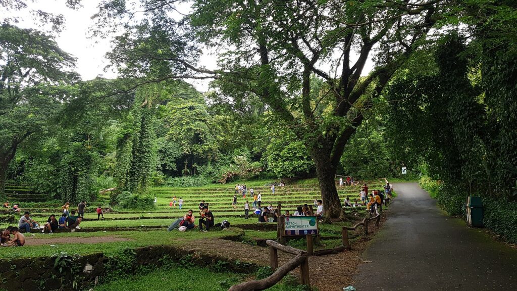 Landschaft mit Amphitheater, Bäume und Menschen, die entspannen.