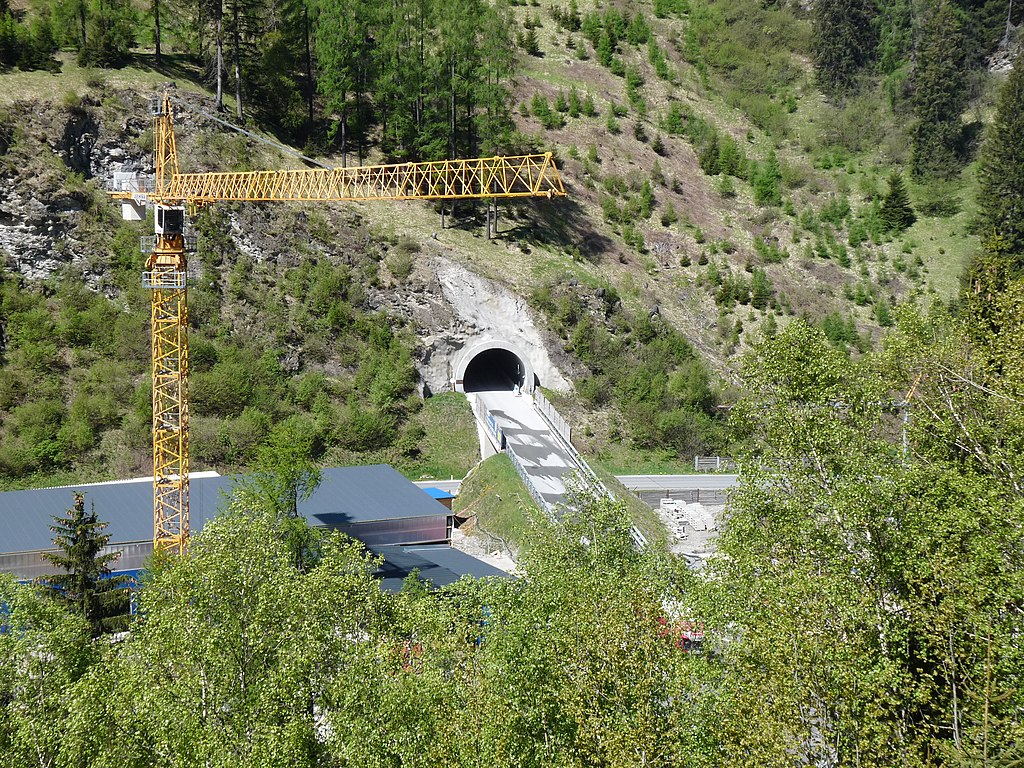 Tunnelbaustelle in alpiner Landschaft mit Baukran.