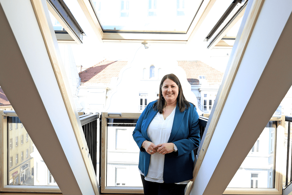Frau auf Balkon mit offenem Dachfenster