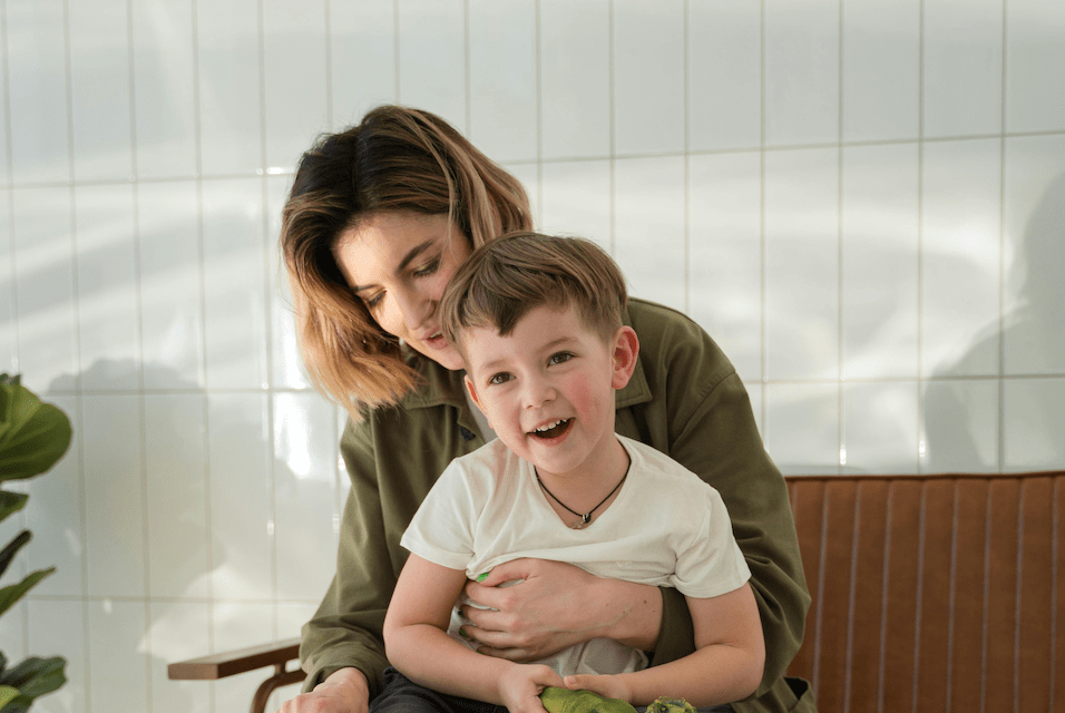Frau spielt mit fröhlichem Kind auf Sofa