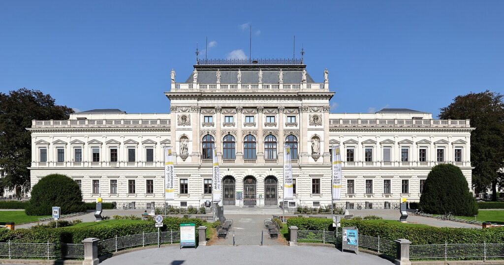 Historisches Gebäude mit Säulen und Statuen, blauer Himmel.