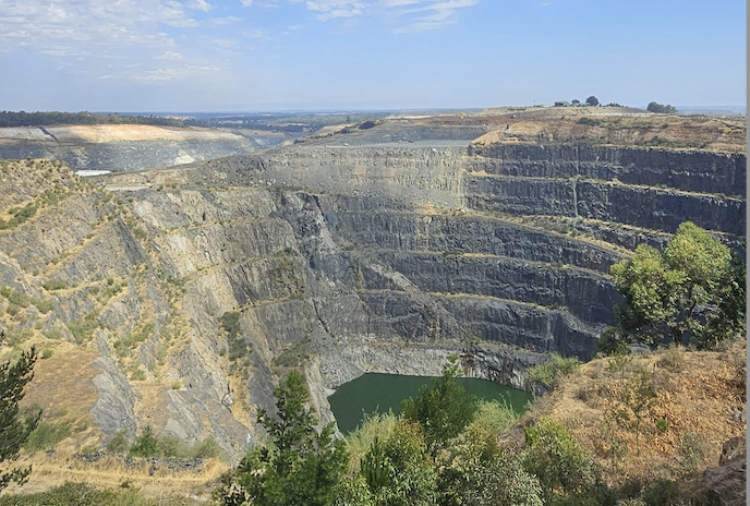 Tiefer Steinbruch mit grünem Wasser in der Mitte.