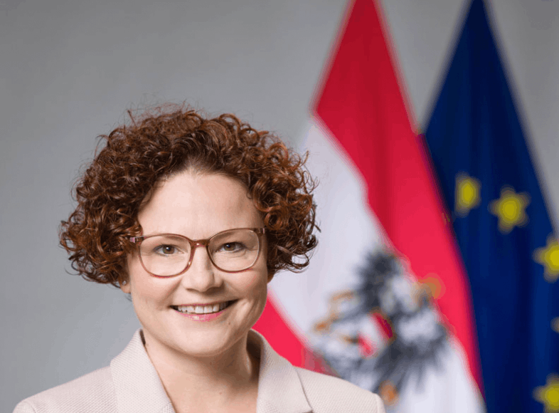 Frau vor Österreich- und EU-Flaggen, lächelnd