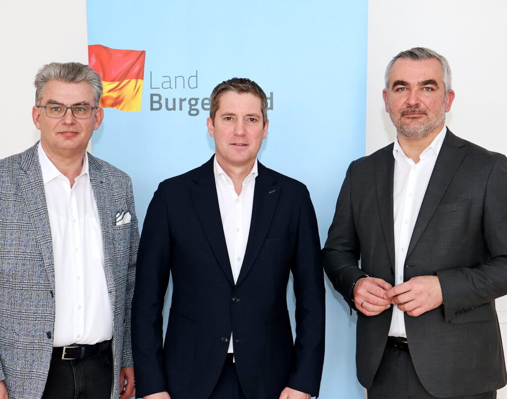 Drei Männer vor Burgenland Hintergrund in Anzügen.