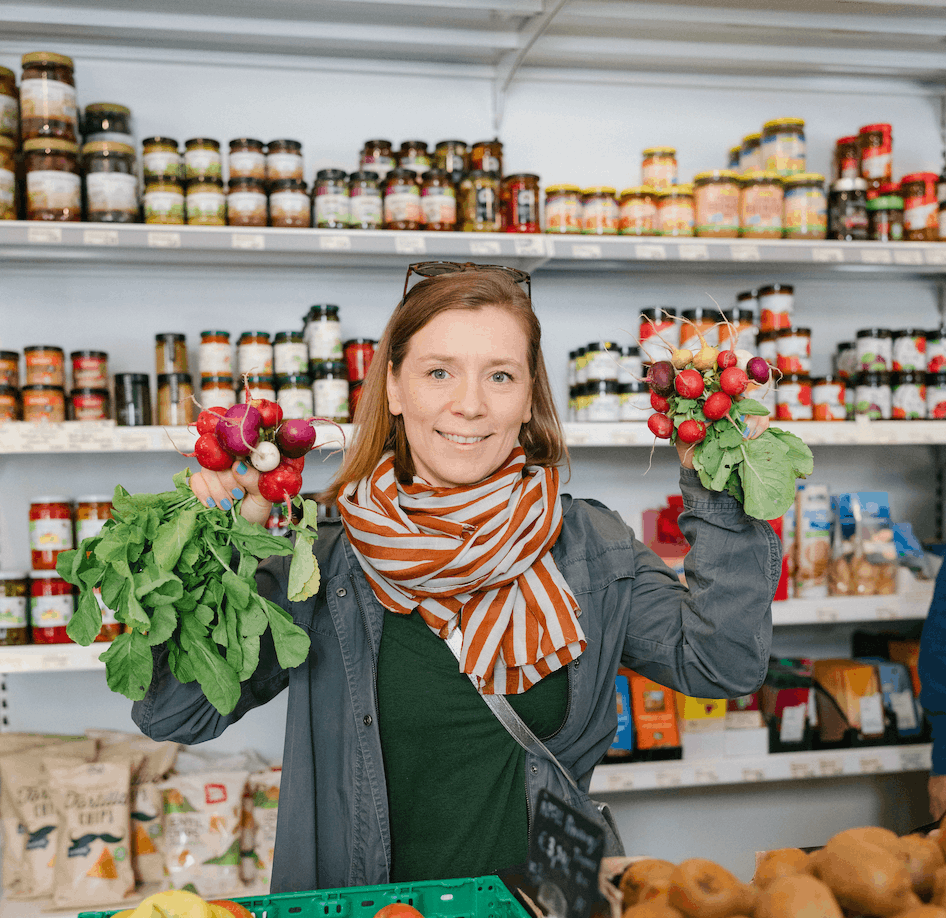 Frau hält Radieschen im Geschäft