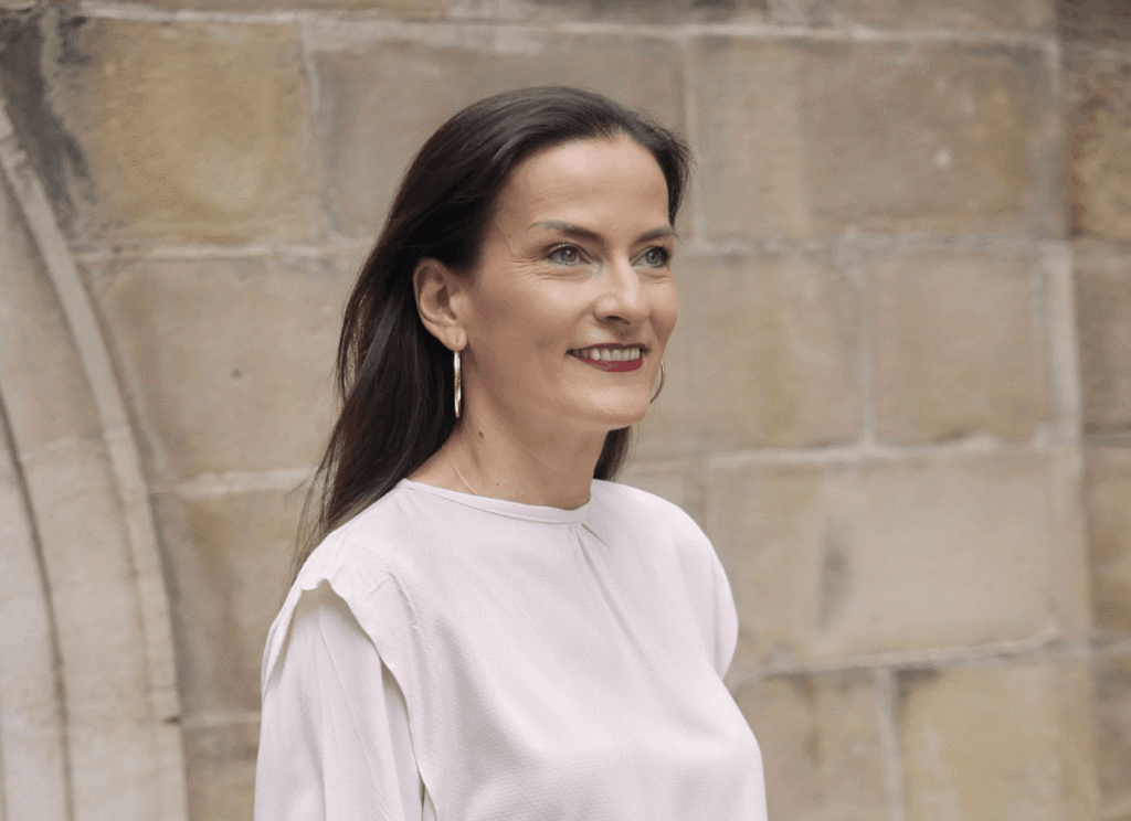 Frau lächelt vor Steinmauer