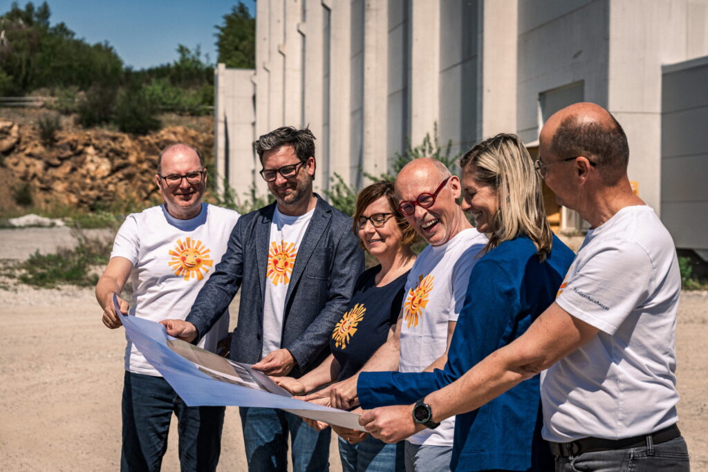 Sechs Personen betrachten Bauplan auf Baustelle