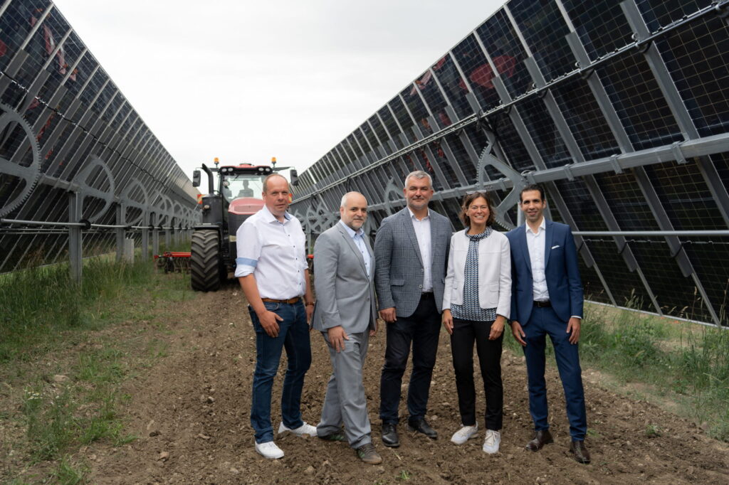 Fünf Personen zwischen Solarpanels und Traktor